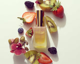 Perfume bottle surrounded by fruits and flowers on a light background